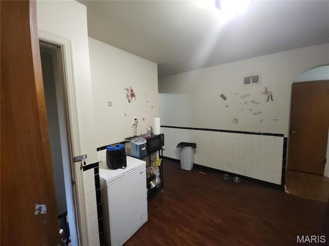 9409 Aetna Dr, Saint Louis, MO 63137 - interior space featuring wood finished floors, arched walkways, tile walls, and wainscoting