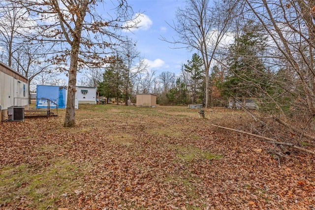 view of yard featuring central AC unit and an outdoor structure