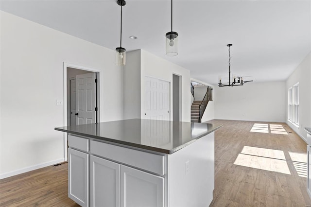 614 Tull Ct, Wentzville, MO 63385 - kitchen with wood finished floors, dark countertops, a chandelier, open floor plan, and baseboards