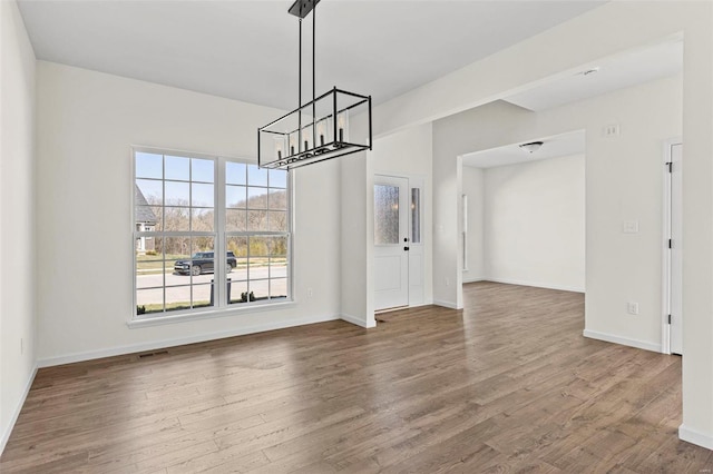 614 Tull Ct, Wentzville, MO 63385 - unfurnished dining area with a chandelier, healthy amount of natural light, and wood finished floors
