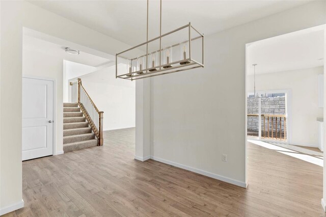409 Fleming Cir, Wentzville, MO 63385 - unfurnished dining area featuring wood finished floors, stairs, and a chandelier