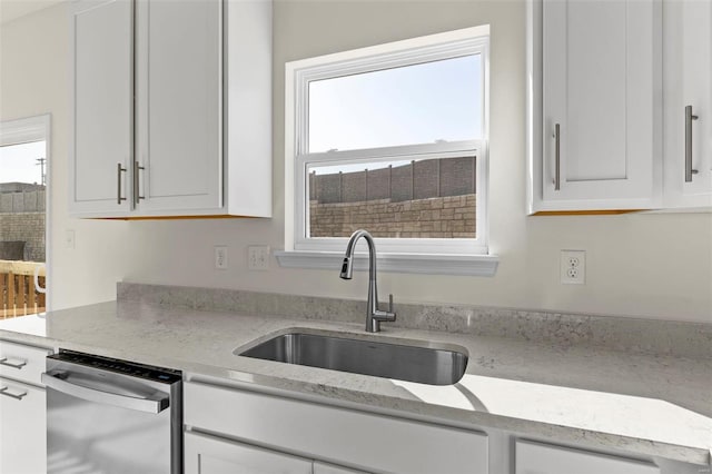 409 Fleming Cir, Wentzville, MO 63385 - kitchen featuring stainless steel dishwasher, a sink, white cabinetry, and light stone countertops