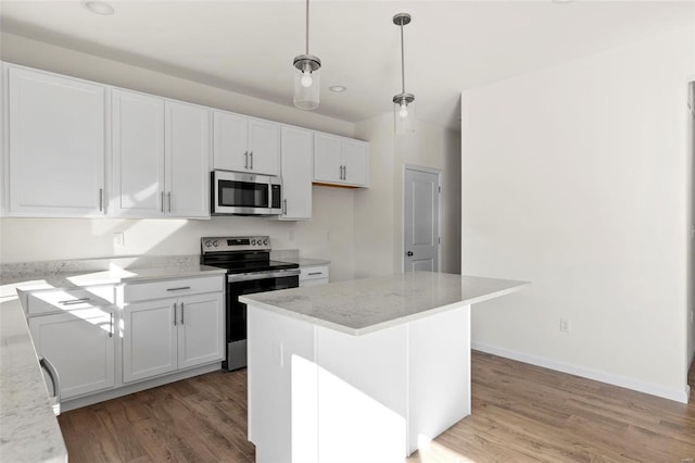 409 Fleming Cir, Wentzville, MO 63385 - kitchen featuring stainless steel appliances, light wood-style floors, white cabinets, and hanging light fixtures