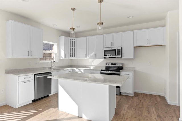 409 Fleming Cir, Wentzville, MO 63385 - kitchen with stainless steel appliances, a sink, white cabinets, light wood finished floors, and glass insert cabinets