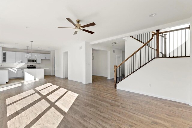 409 Fleming Cir, Wentzville, MO 63385 - unfurnished living room featuring light wood-style floors, stairway, baseboards, and a ceiling fan