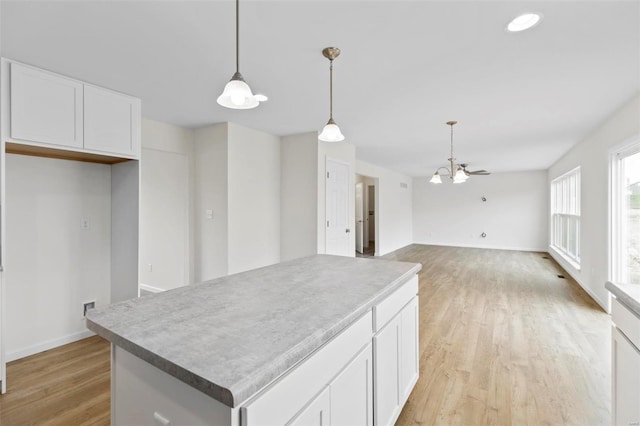 411 Fleming Cir, Wentzville, MO 63385 - kitchen featuring light wood-style floors, white cabinets, hanging light fixtures, a kitchen island, and a chandelier