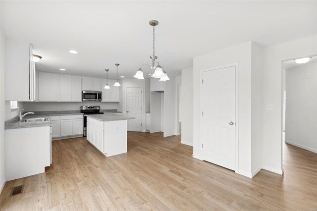 411 Fleming Cir, Wentzville, MO 63385 - kitchen featuring appliances with stainless steel finishes, a sink, white cabinetry, a kitchen island, and light wood-style floors