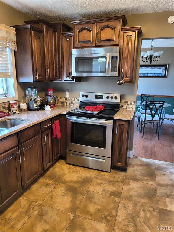 10740 Wilmena Ln, Rolla, MO 65401 - kitchen featuring stainless steel appliances, a textured ceiling, light countertops, a sink, and a chandelier