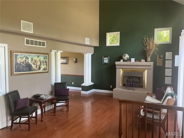 10740 Wilmena Ln, Rolla, MO 65401 - living room featuring ornate columns, wood finished floors, a fireplace with raised hearth, and a high ceiling