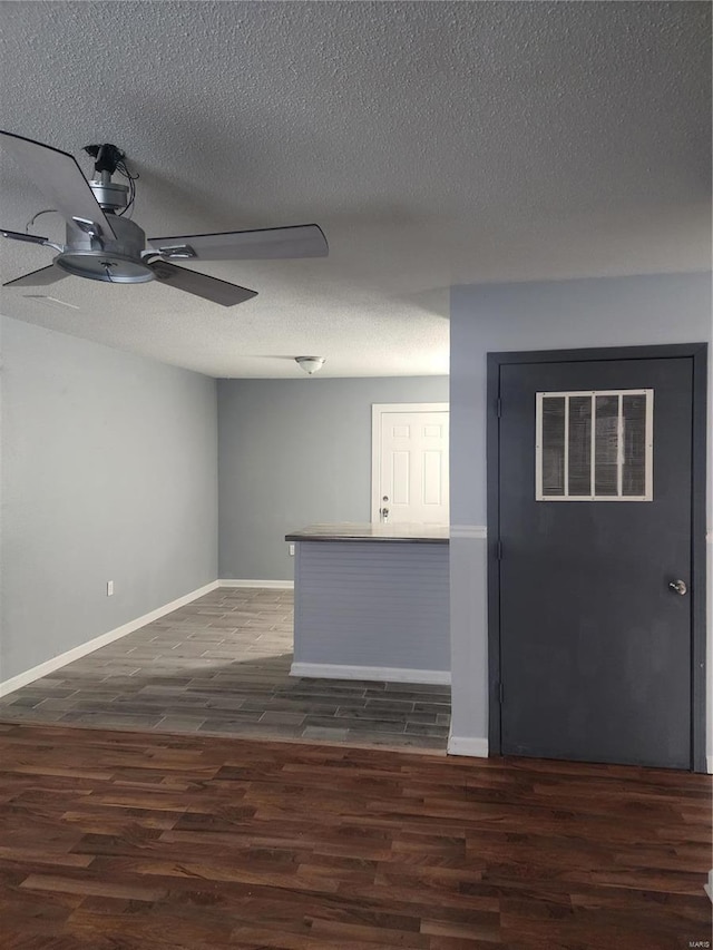 unfurnished room with dark wood-type flooring, ceiling fan, baseboards, and a textured ceiling