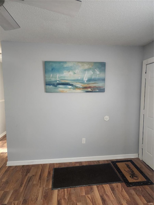 unfurnished room featuring wood finished floors, baseboards, and a textured ceiling