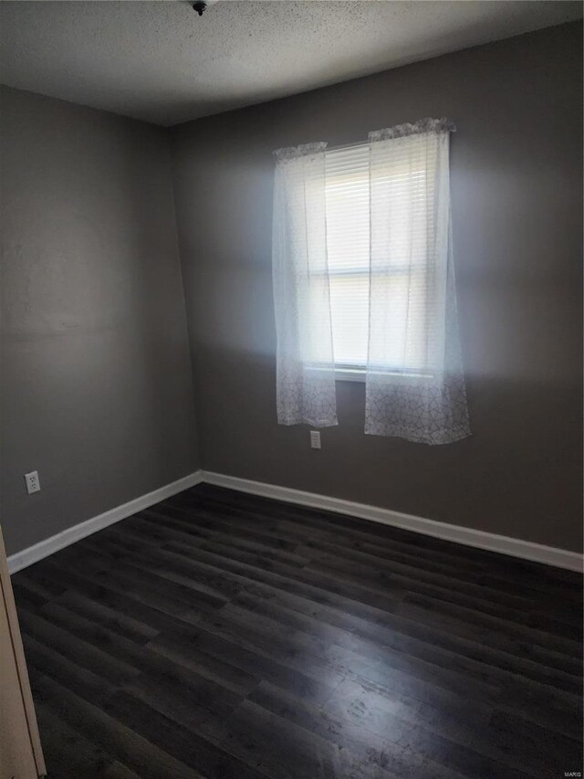 spare room with dark wood-style flooring, baseboards, and a textured ceiling