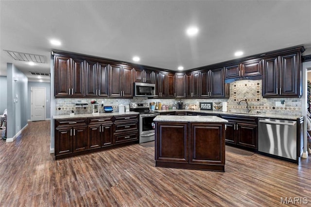 216 Sherrie Dr, Sikeston, MO 63801 - kitchen with stainless steel appliances, backsplash, dark brown cabinetry, dark wood finished floors, and light stone countertops