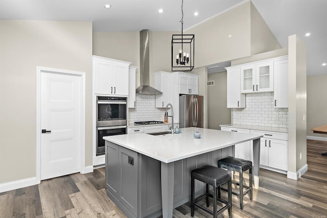 3526 Red Oak Dr, Imperial, MO 63052 - kitchen featuring appliances with stainless steel finishes, wall chimney range hood, a sink, wood finished floors, and light countertops
