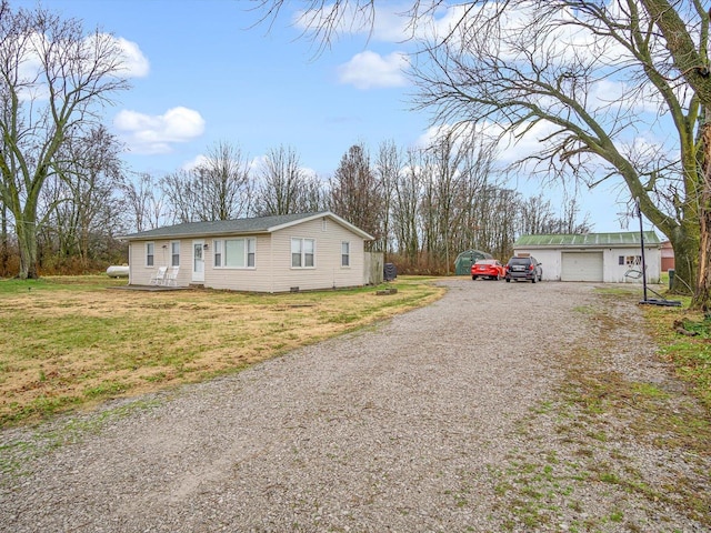 view of front of house with driveway, a detached garage, and a front yard