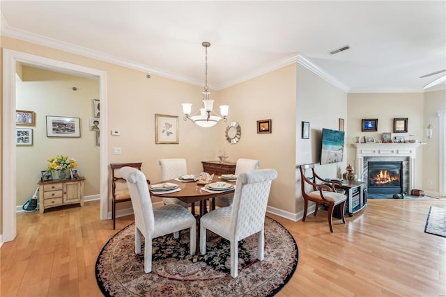 13101 Mill Crossing Ct Unit 307, Creve Coeur, MO 63141 - dining room with light wood-type flooring, ornamental molding, baseboards, a warm lit fireplace, and a chandelier