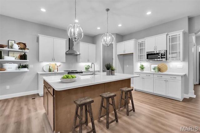 201 Keaton Woods Dr, Ofallon, MO 63368 - kitchen with stainless steel appliances, wall chimney exhaust hood, a sink, light countertops, and light wood finished floors