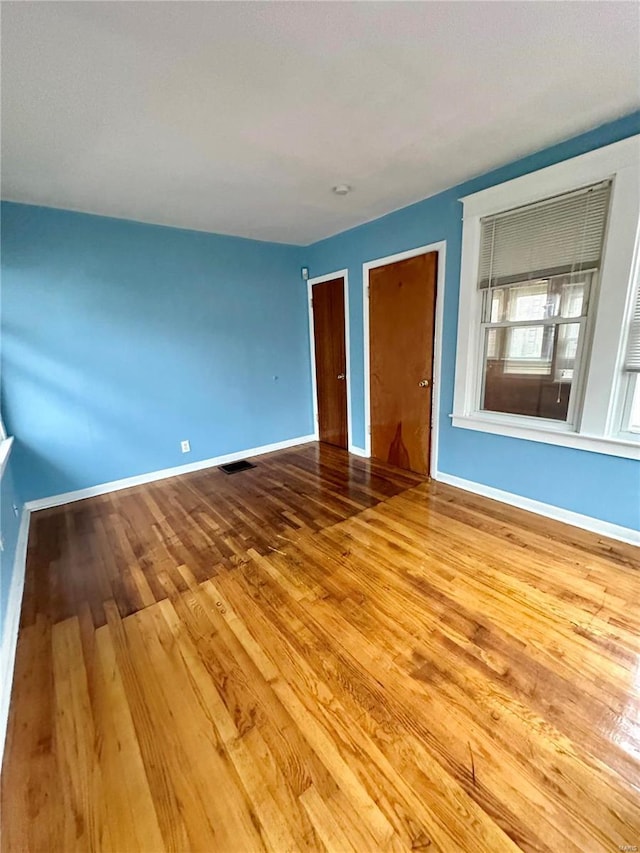 4025 Tholozan Ave, Saint Louis, MO 63116 - unfurnished bedroom with wood finished floors, baseboards, and multiple closets