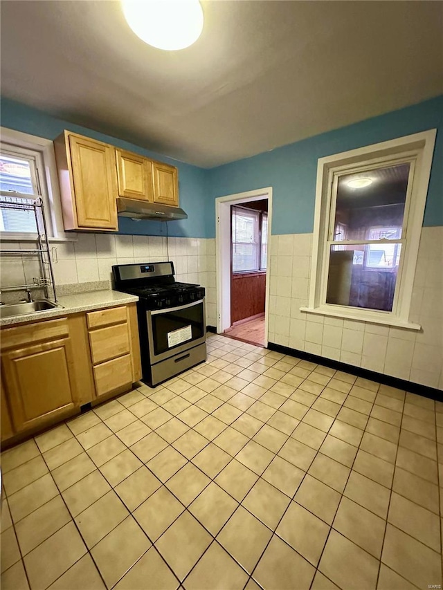 4025 Tholozan Ave, Saint Louis, MO 63116 - kitchen featuring stainless steel range with gas cooktop, a sink, light countertops, under cabinet range hood, and tile walls