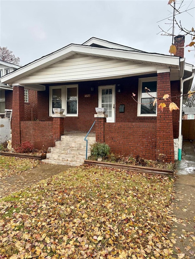 4025 Tholozan Ave, Saint Louis, MO 63116 - view of front of house with a chimney, brick siding, a porch, and fence