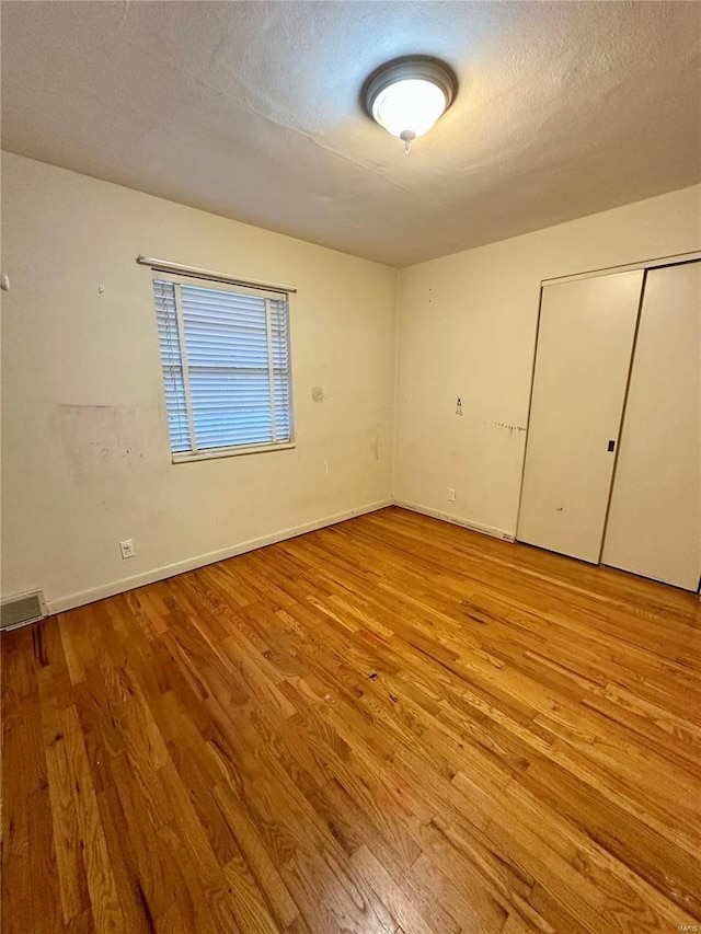 4828 Reavis Barracks Rd, Saint Louis, MO 63123 - unfurnished bedroom with wood finished floors, baseboards, a closet, and a textured ceiling