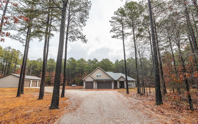 view of front facade featuring driveway, a wooded view, and an attached garage