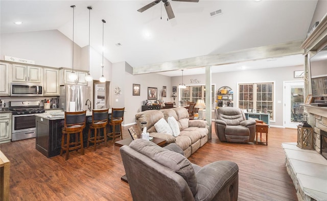 living area with a ceiling fan, high vaulted ceiling, dark wood-style floors, baseboards, and a fireplace