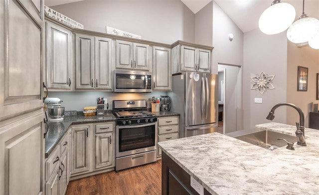 kitchen with stainless steel appliances, a sink, high vaulted ceiling, decorative light fixtures, and dark wood-style floors