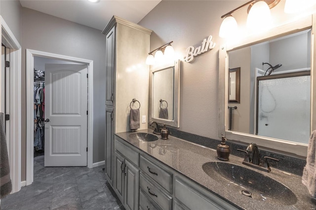 full bath featuring an enclosed shower, double vanity, a walk in closet, and baseboards