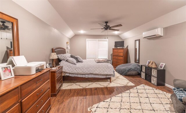 bedroom featuring a wall unit AC, vaulted ceiling, wood finished floors, baseboards, and a ceiling fan
