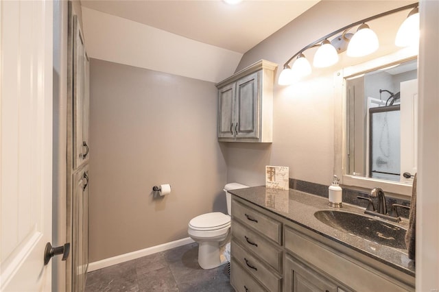 bathroom with toilet, vanity, baseboards, and vaulted ceiling