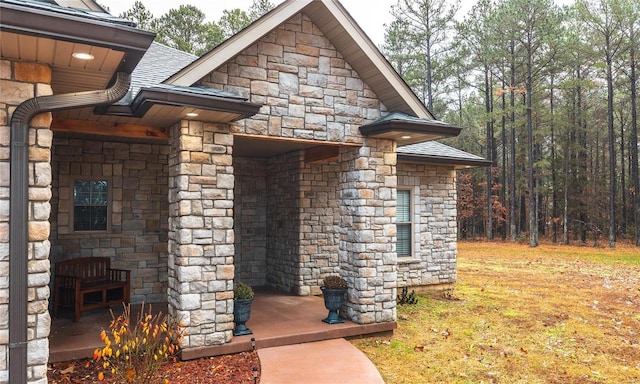 view of side of home featuring stone siding and roof with shingles
