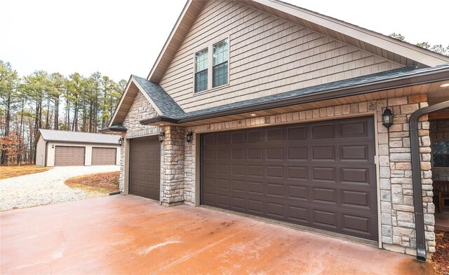view of property exterior with stone siding, a shingled roof, and driveway