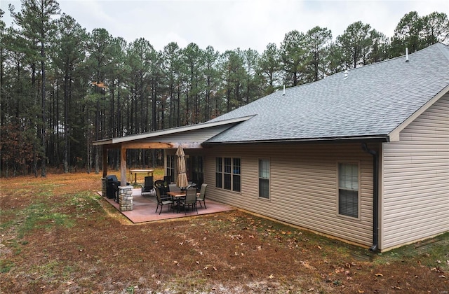 rear view of house featuring a shingled roof and a patio