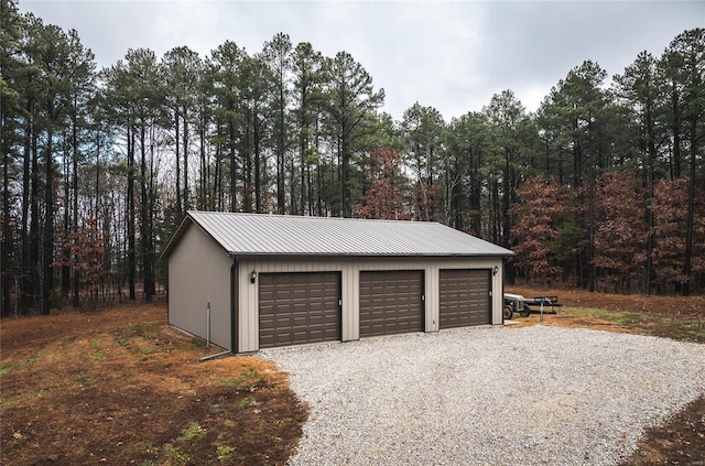 detached garage featuring a view of trees