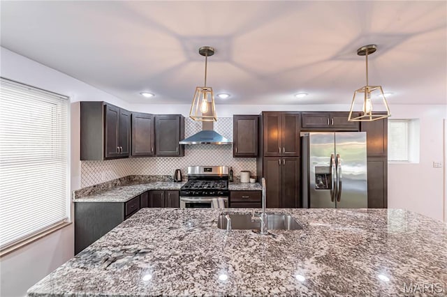 1101 W Parkedge Ln, Saint Louis, MO 63130 - kitchen featuring appliances with stainless steel finishes, wall chimney exhaust hood, dark brown cabinetry, dark stone counters, and hanging light fixtures