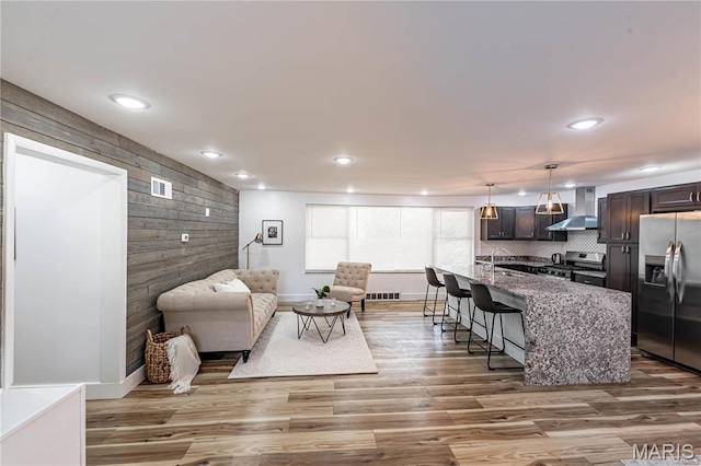1101 W Parkedge Ln, Saint Louis, MO 63130 - living room with an accent wall, recessed lighting, wood finished floors, and wooden walls
