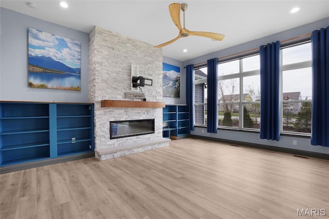 215 Wyndemere Ln, Lake St Louis, MO 63367 - unfurnished living room with plenty of natural light, wood finished floors, a stone fireplace, a ceiling fan, and recessed lighting