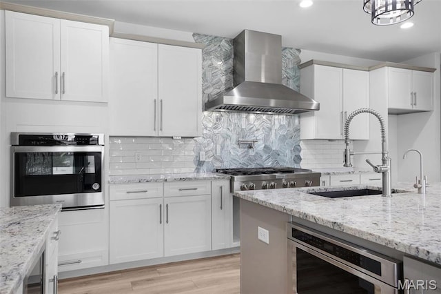 215 Wyndemere Ln, Lake St Louis, MO 63367 - kitchen featuring wall chimney exhaust hood, appliances with stainless steel finishes, a sink, light wood-type flooring, and white cabinets