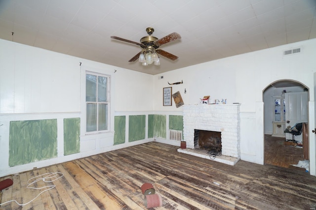 212 N Main St, Licking, MO 65542 - unfurnished living room with hardwood / wood-style floors, a brick fireplace, a ceiling fan, and arched walkways