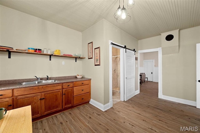 16683 Mill Rd, Marthasville, MO 63357 - kitchen with open shelves, a barn door, brown cabinets, light wood-type flooring, and crown molding