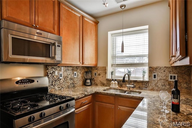 kitchen featuring stainless steel appliances, a sink, light stone countertops, decorative backsplash, and pendant lighting