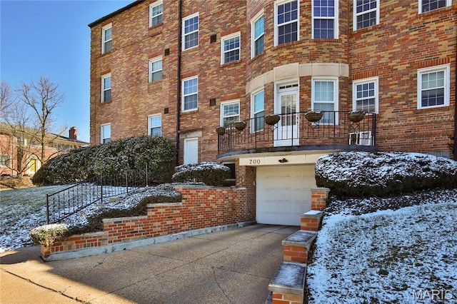view of front facade with brick siding, an attached garage, and driveway