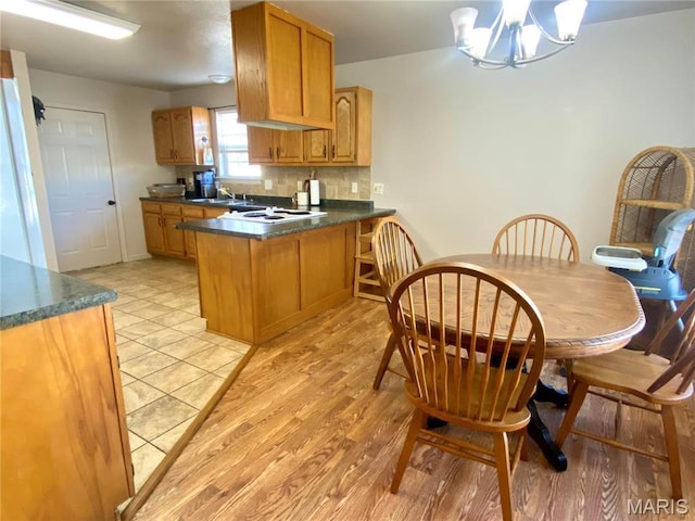 914 Pine St, Sikeston, MO 63801 - kitchen with a peninsula, dark countertops, a chandelier, and brown cabinets