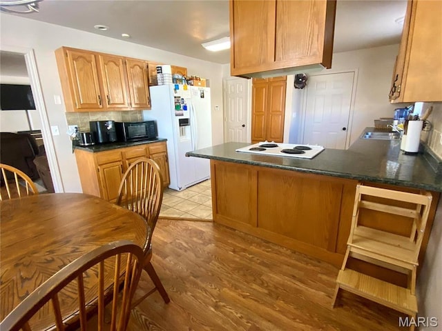 914 Pine St, Sikeston, MO 63801 - kitchen with white appliances, dark countertops, a peninsula, light wood finished floors, and recessed lighting