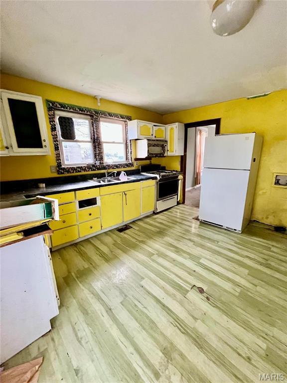 209 Mcgill St, Jerseyville, IL 62052 - kitchen with white appliances, light wood finished floors, dark countertops, and a sink