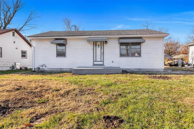 bungalow with a front lawn and a shingled roof