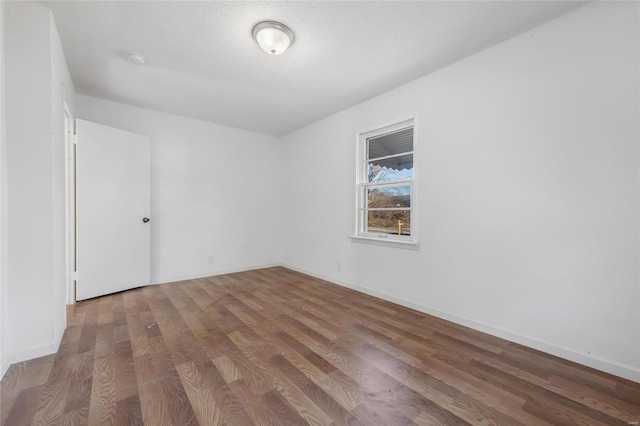 unfurnished room featuring wood finished floors, baseboards, and a smoke detector