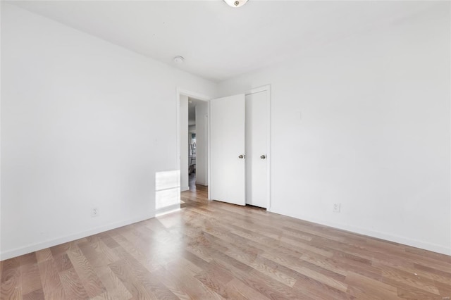 spare room featuring light wood-style floors and baseboards