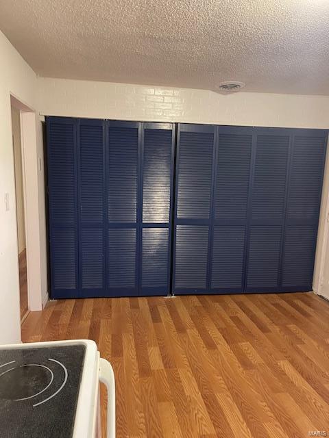 unfurnished room with a textured ceiling and wood finished floors